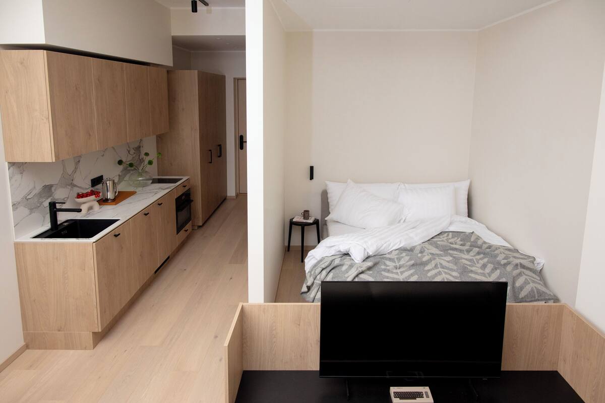 Habitación compacta con kitchenette a un lado y una cama al otro.