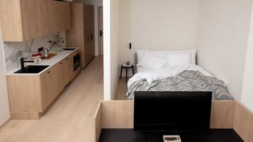Ein kleines Zimmer mit einer Küchenzeile an einer Seite und einem Bett auf der anderen Seite.