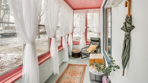 A cozy room with a red ceiling, white curtains, a rocking chair, a small ottoman, and a wooden side table. - Charming Minneapolis Home w/ Deck, 5 Mi to Central (Minneapolis)