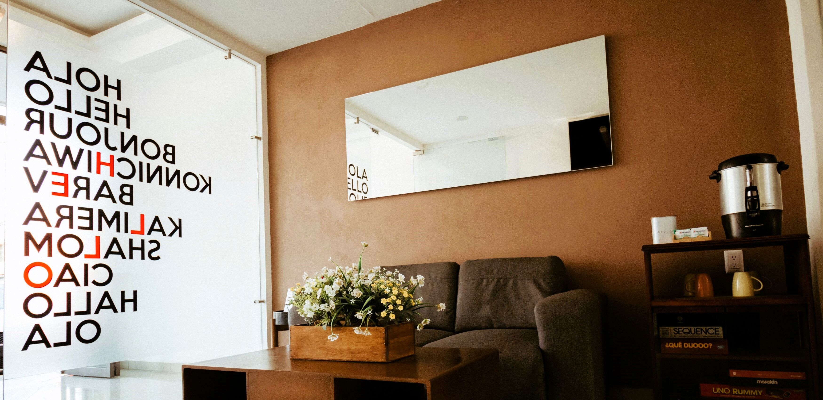 Una sala de estar moderna con un sofá, una mesa de centro con flores, una estantería y un espejo grande en la pared.