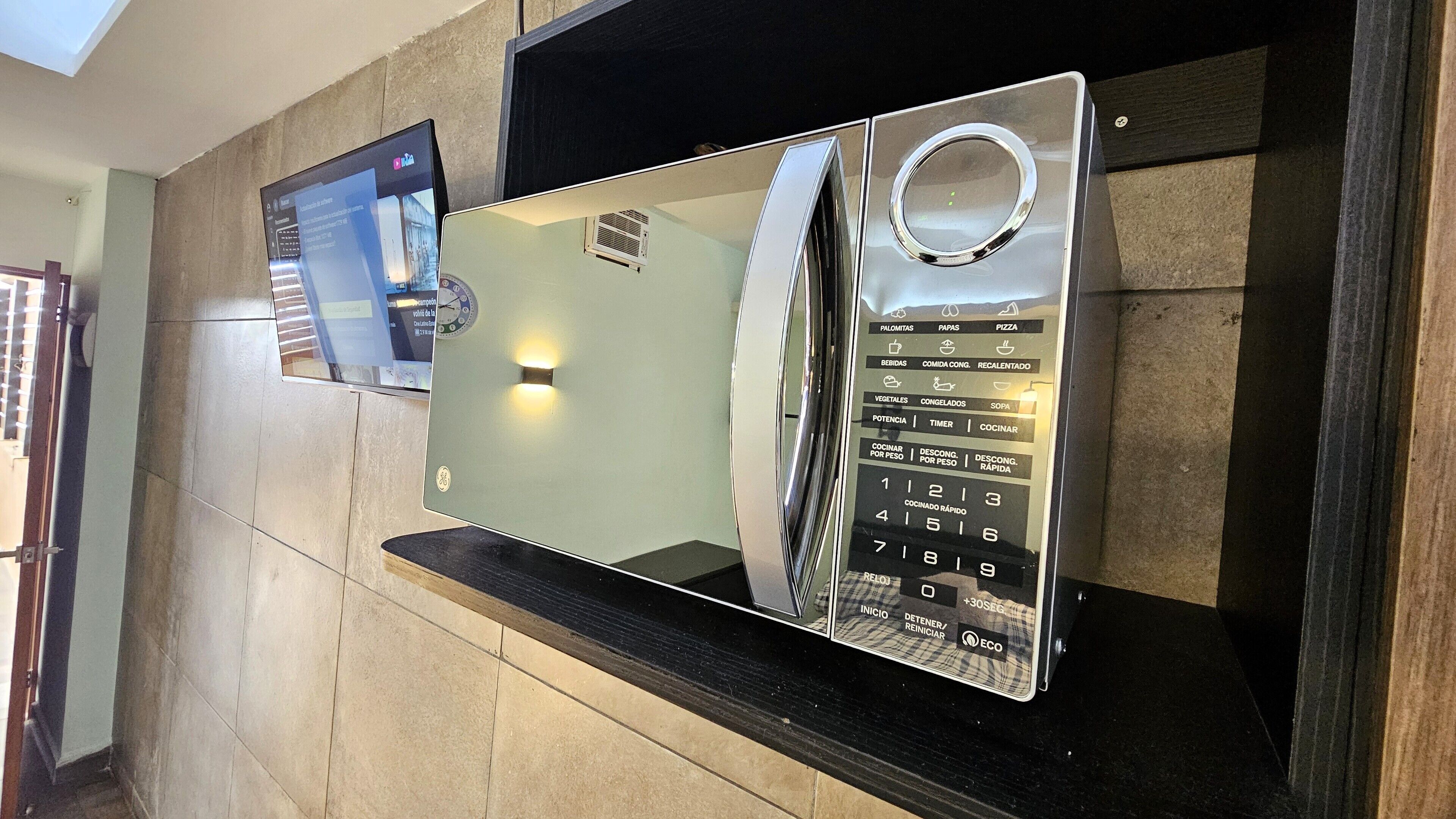 A wall-mounted microwave with a digital display and multiple cooking settings.