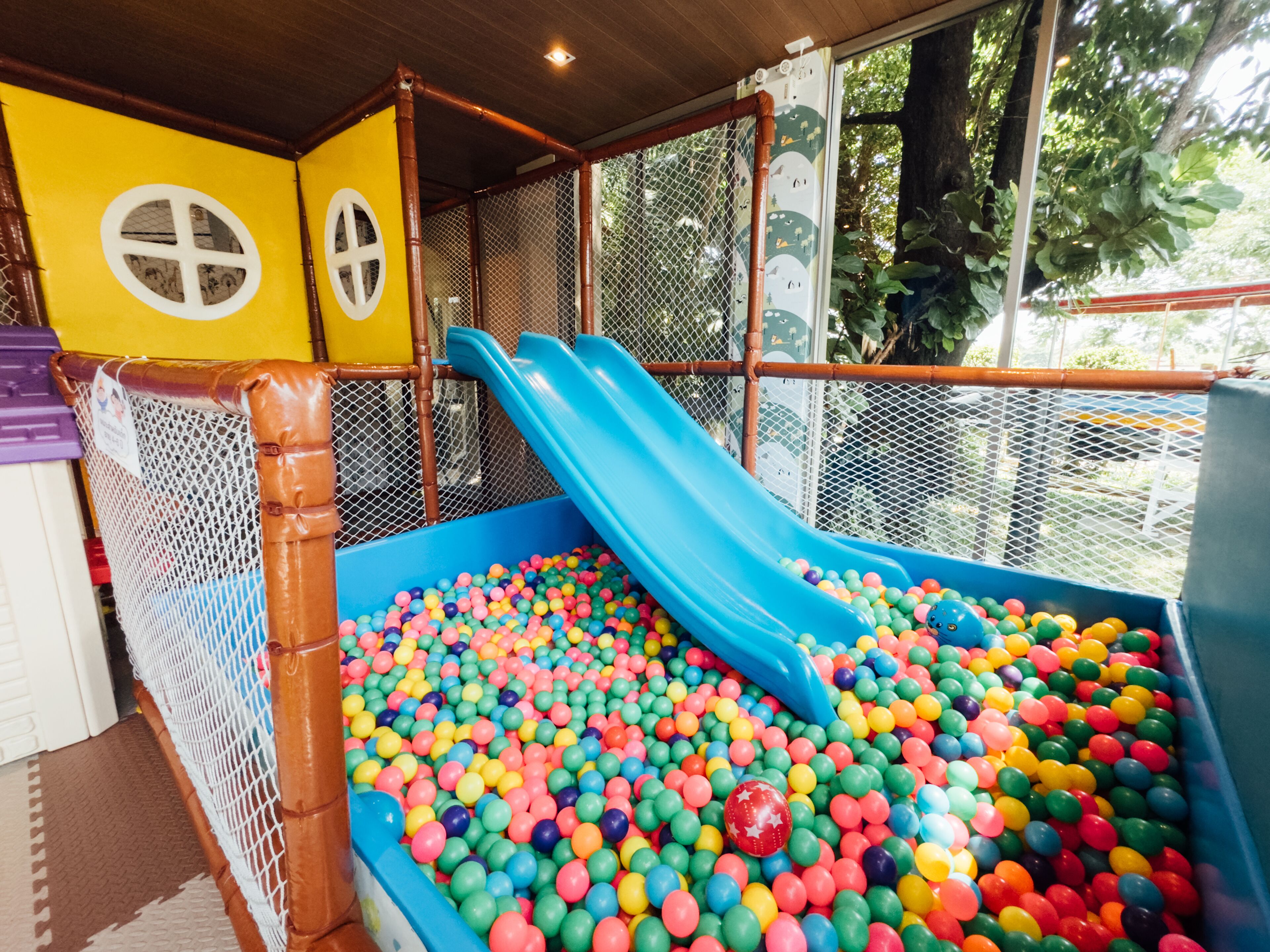 Zona de juegos infantiles con un tobogán y una piscina de pelotas llena de bolas de colores.