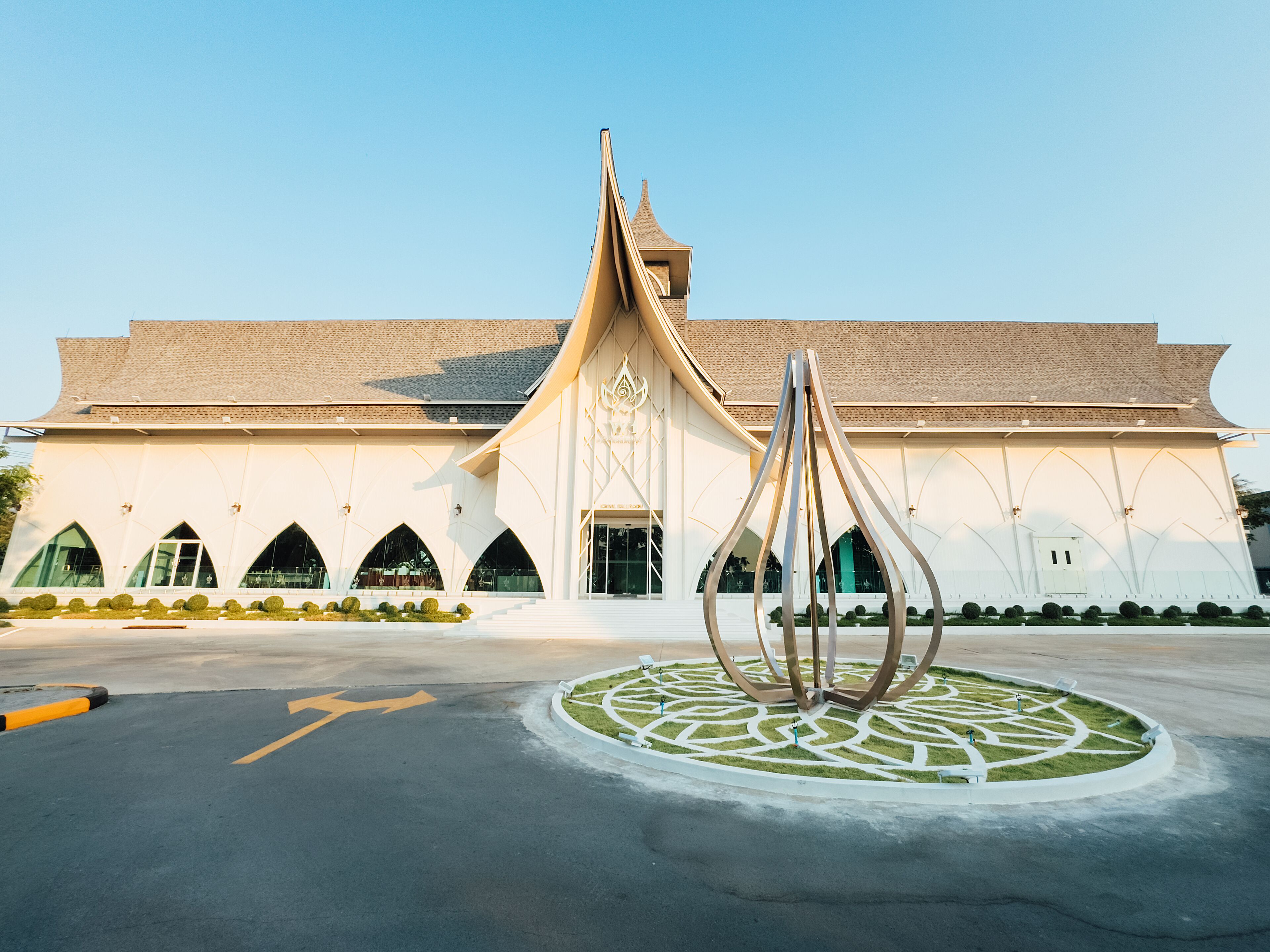 A building with a modern architectural design, featuring a central sculpture and a landscaped area in front.