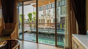 A room with a large sliding glass door leading to a pool area, a wooden chair, and a marble table.