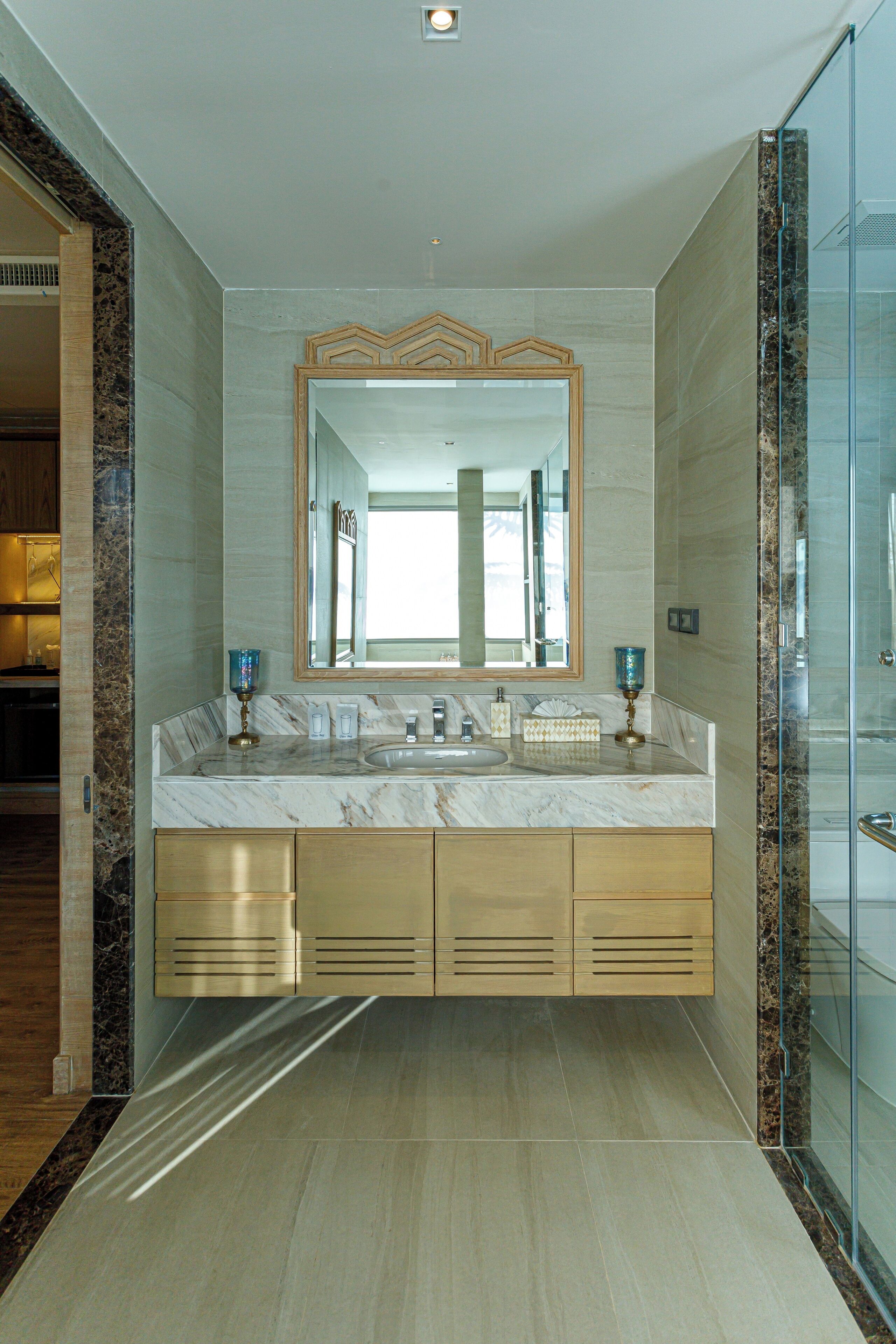 A modern bathroom with a marble vanity, a large mirror, and a glass shower enclosure.