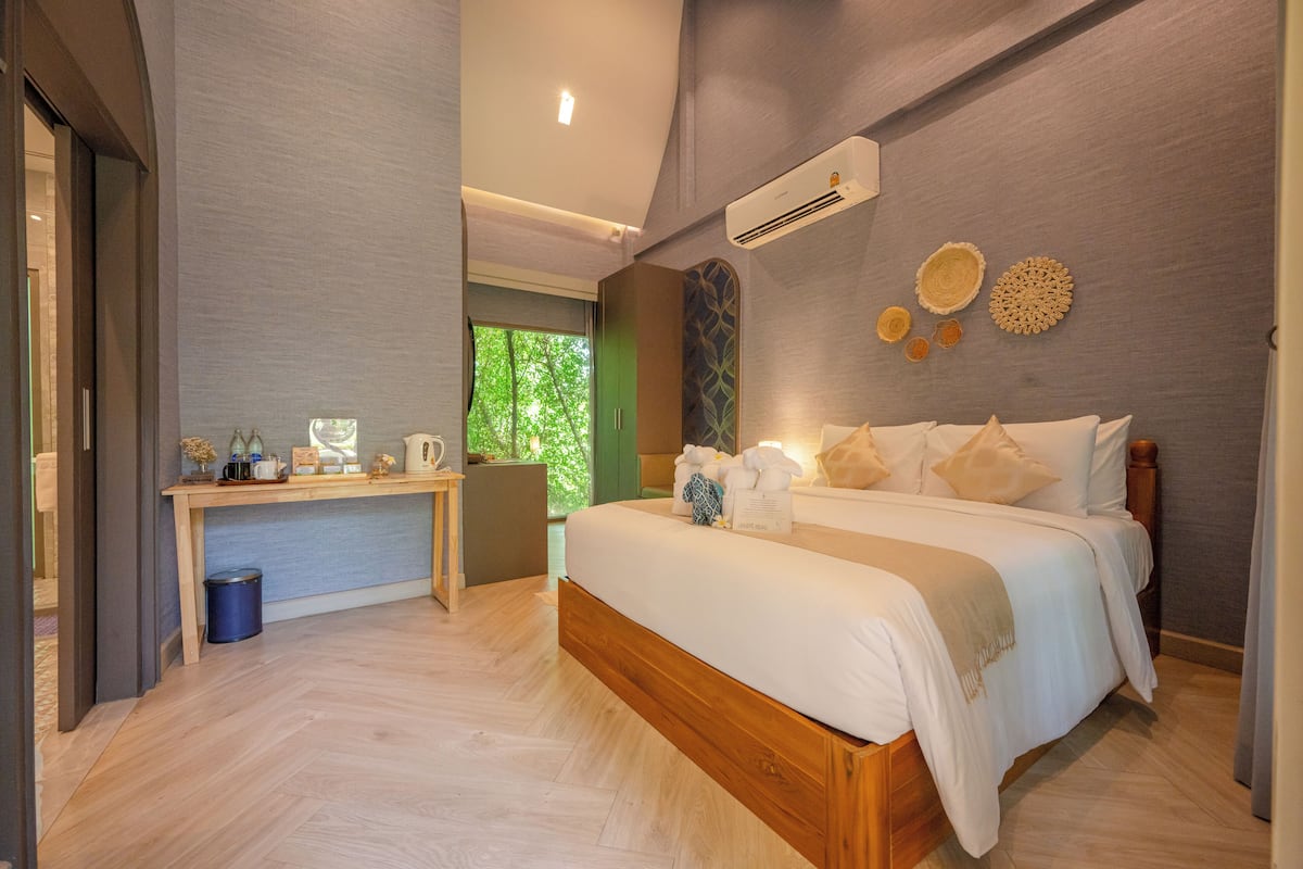 Une chambre moderne avec un lit en bois, un bureau et une vue sur la verdure.