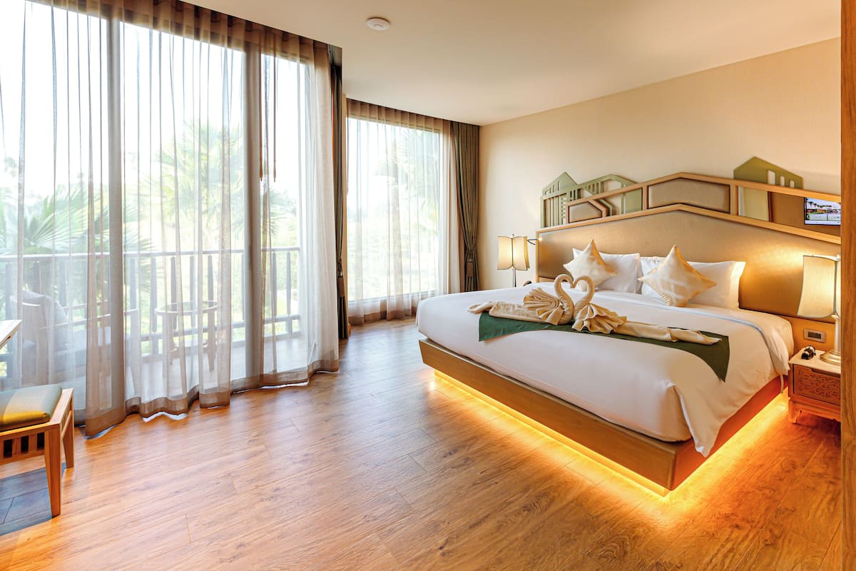 Une chambre d’hôtel avec un grand lit, un bureau et un balcon avec des rideaux.