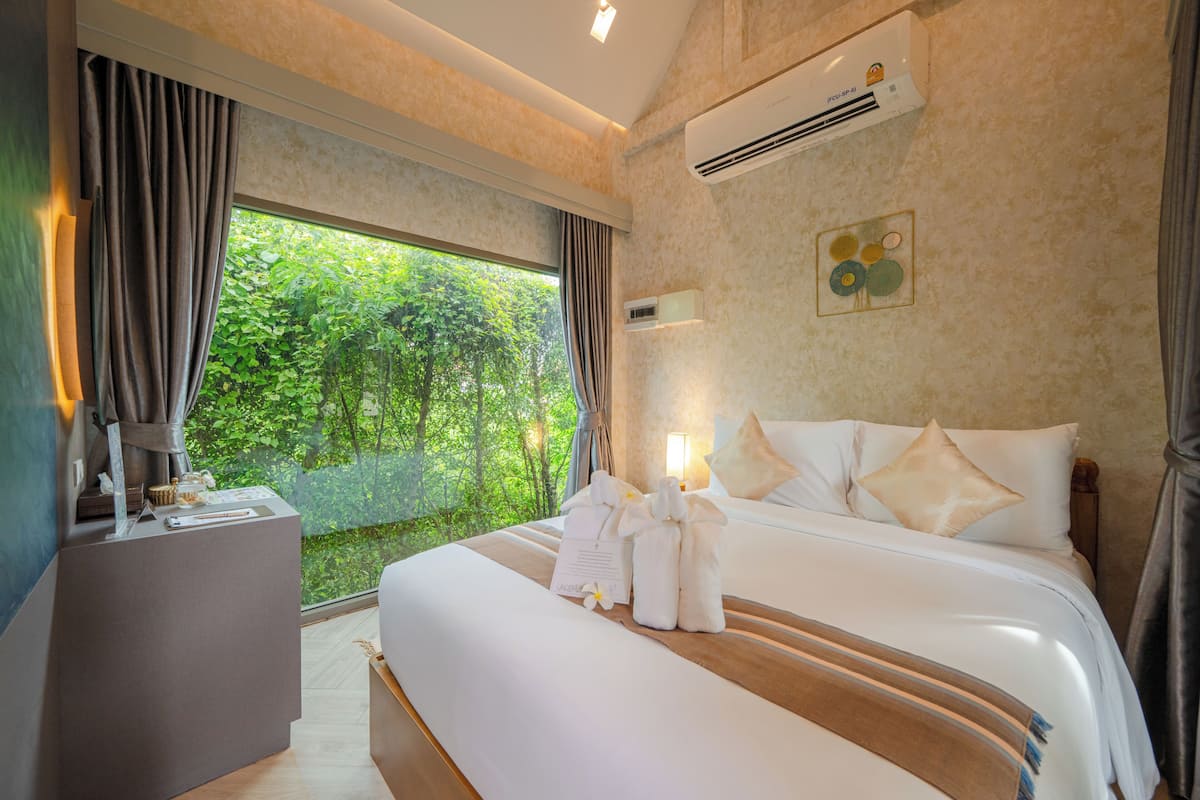 Une chambre d’hôtel avec un grand lit, une table de chevet, un bureau et une fenêtre avec des rideaux.