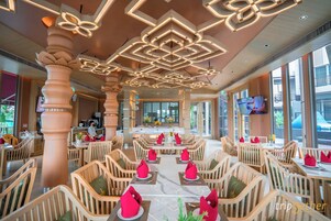Un restaurante espacioso con techos altos, iluminación moderna y cómodas sillas de madera.