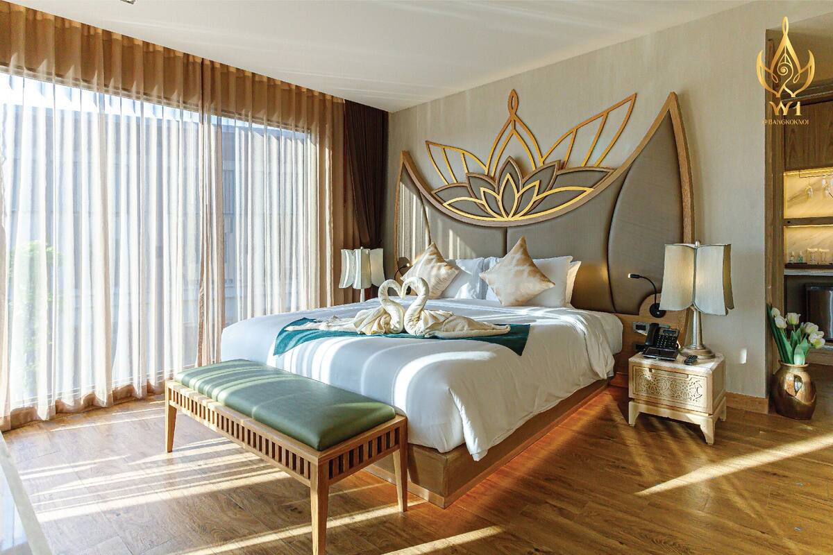 Une chambre spacieuse avec un grand lit, une table de chevet avec une lampe et un élément décoratif mural.