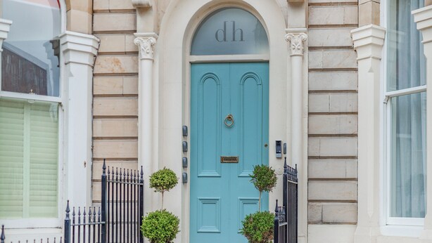 A blue door with a 'dh' sign above it, flanked by two potted plants and a black metal fence. - Derwent House Apartments - Harwood - UK46786 (Scarborough)