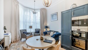 A modern kitchen with a built-in oven, a dining area with a round table and four chairs, and a seating area with two armchairs and a sofa. - Derwent House Apartments - Harwood - UK46786 (Scarborough)
