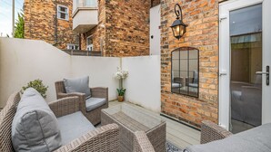 A brick building with a glass door, wicker furniture, and a potted plant. - Derwent House Apartments - Harwood - UK46786 (Scarborough)