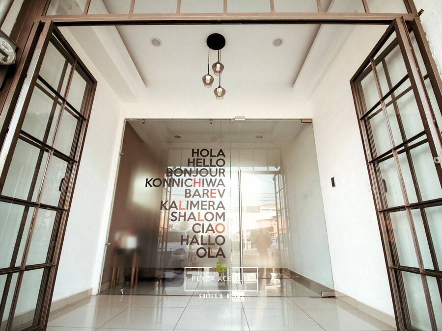 A hotel entrance with a glass door and a sign displaying greetings in multiple languages.