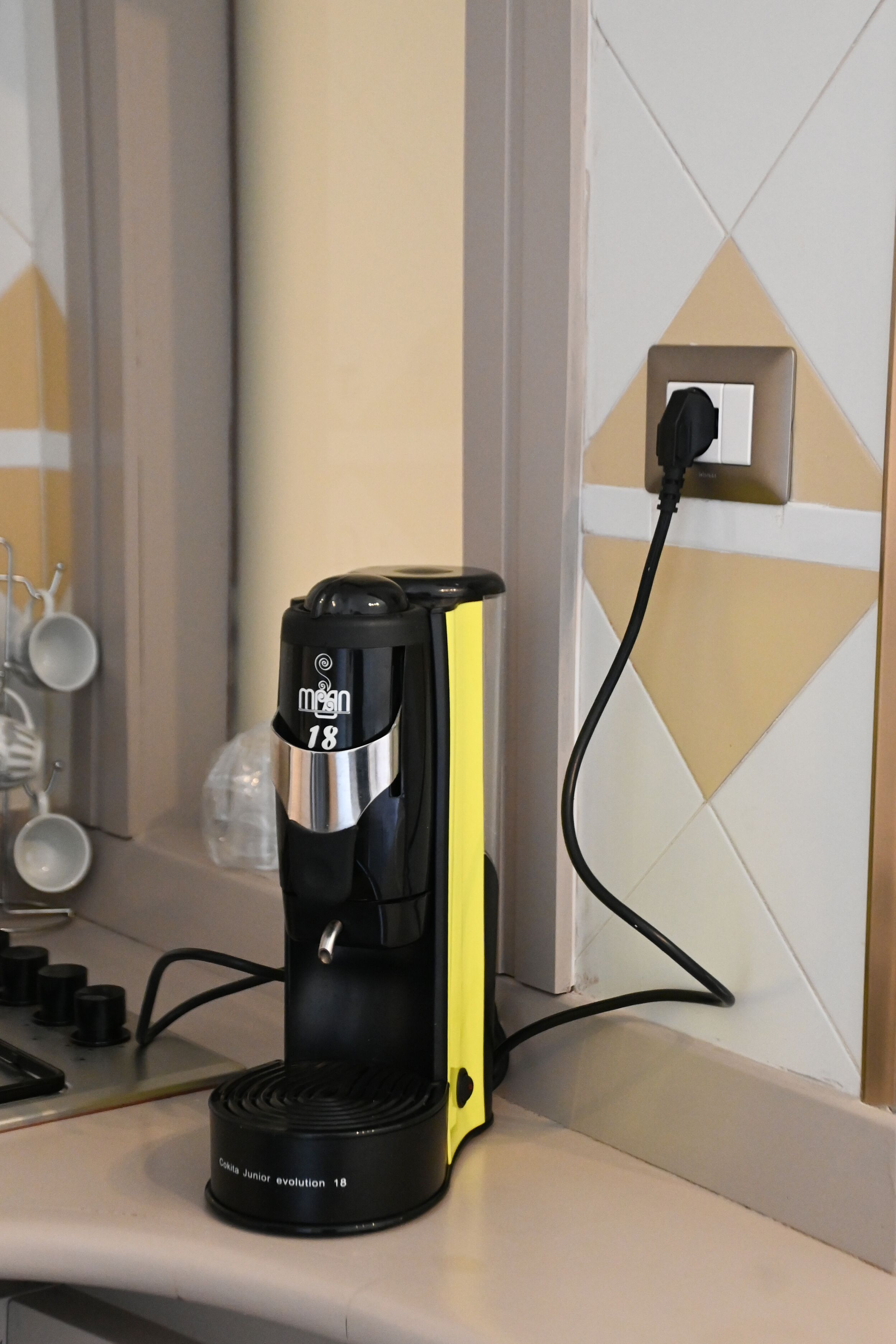 A coffee maker on a kitchen counter with a power outlet nearby.