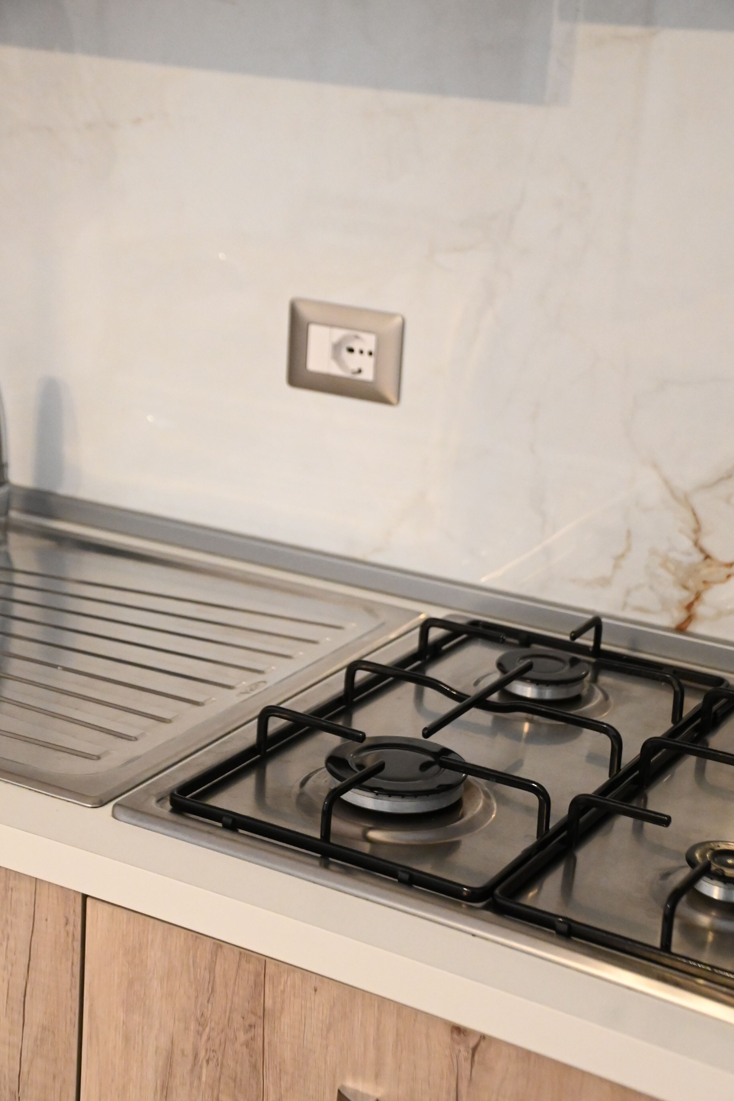 A kitchen with a gas stove, a countertop, and a marble backsplash.