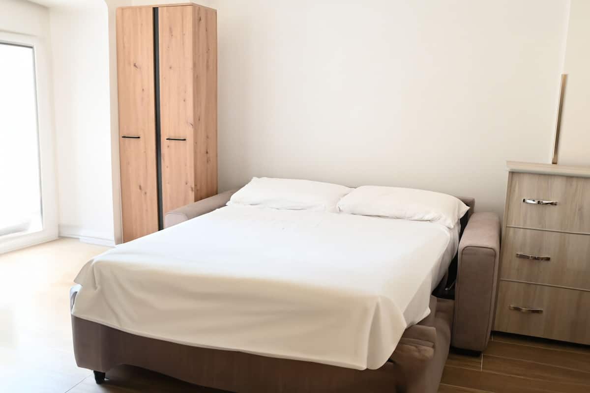 A bedroom with a bed, wooden wardrobe, and a small cabinet.