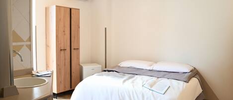 A modern bedroom with a bed, bedside table, and a wardrobe.