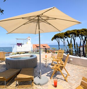 Un espace extérieur aménagé avec un bain à remous, des chaises longues et un grand parasol.