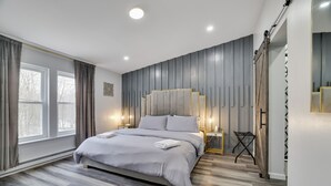A modern bedroom with a large bed, bedside lamps, a wardrobe, and a view of the outdoors.