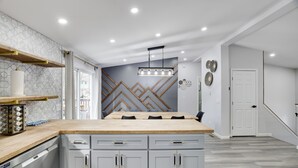 A modern kitchen with a central island, grey cabinets, and a wooden countertop.