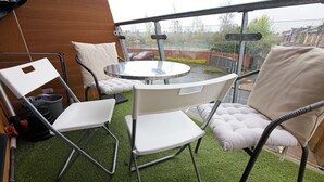 A balcony with a round table and two white chairs, one with a cushioned backrest. - Manchester Retreat - Modern 2Br Apartment (Manchester)