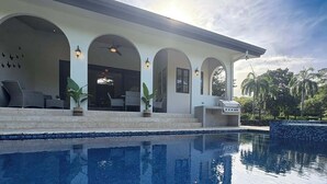 Una casa moderna con piscina, area salotto esterna e barbecue.