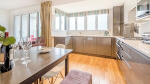 Eine moderne Küche mit Essbereich, großen Fenstern und Blick ins Freie.