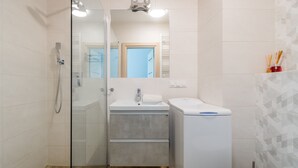 A modern bathroom with a glass shower enclosure, a sink with a mirror above, and a toilet. - Jaglana Deluxe by Grand Apartments (Gdansk)
