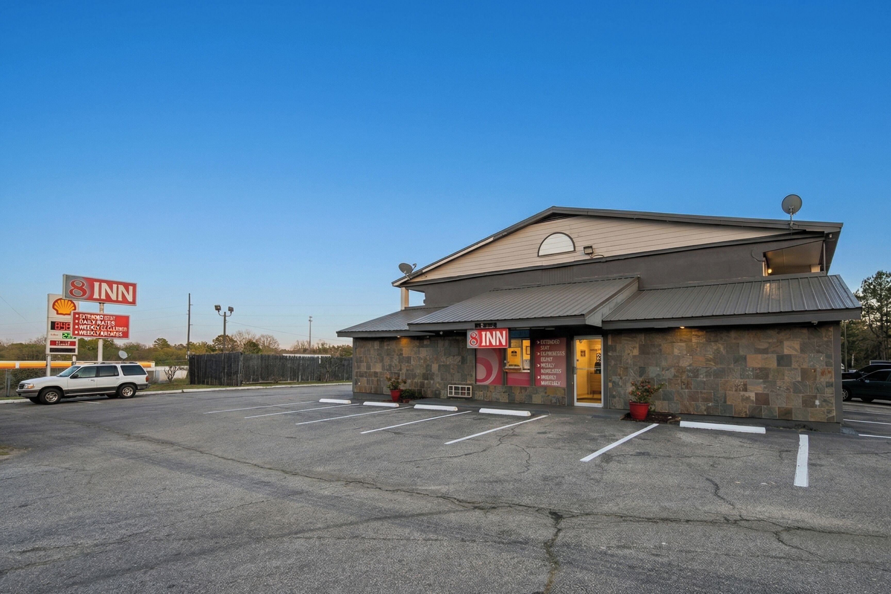 A 3-story building with a 8 Inn sign, a Shell gas station, and a parking lot.