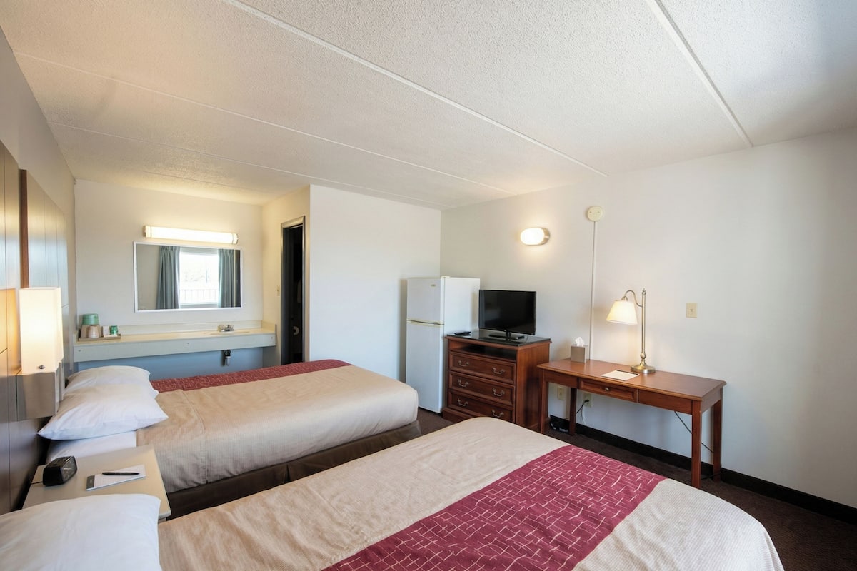 Une chambre d’hôtel avec deux lits, un bureau, une télévision et un miroir.