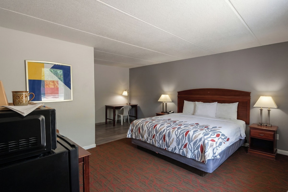 Une chambre d’hôtel comprenant un lit, des lampes de chevet, un bureau, une chaise et un téléviseur.