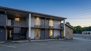 Un motel de varios pisos con balcones, un acceso cubierto y plantas en macetas.