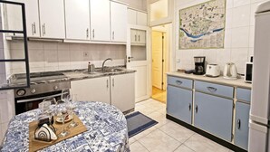 A compact kitchen with white cabinets, a marble countertop, and a dining area with a patterned tablecloth. - Inviting 2-bed Apartment in Porto (Porto)