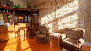A cozy room with a stone wall, wooden furniture, and a bar area with bottles. - Inviting 2-bed Apartment in Porto (Porto)