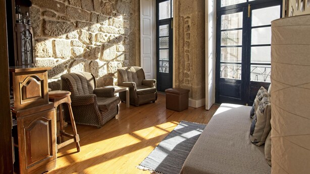 A room with stone walls, wooden furniture, and large windows. - Inviting 2-bed Apartment in Porto (Porto)