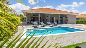 A modern house with a swimming pool, covered patio, and lounge chairs.