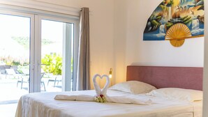 A hotel room with a bed, a large window, and a painting of a waterfall.