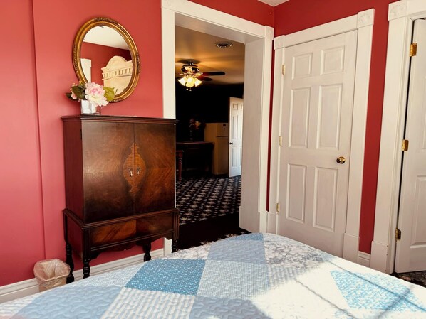 Un dormitorio con cama, cómoda, espejo y puerta.