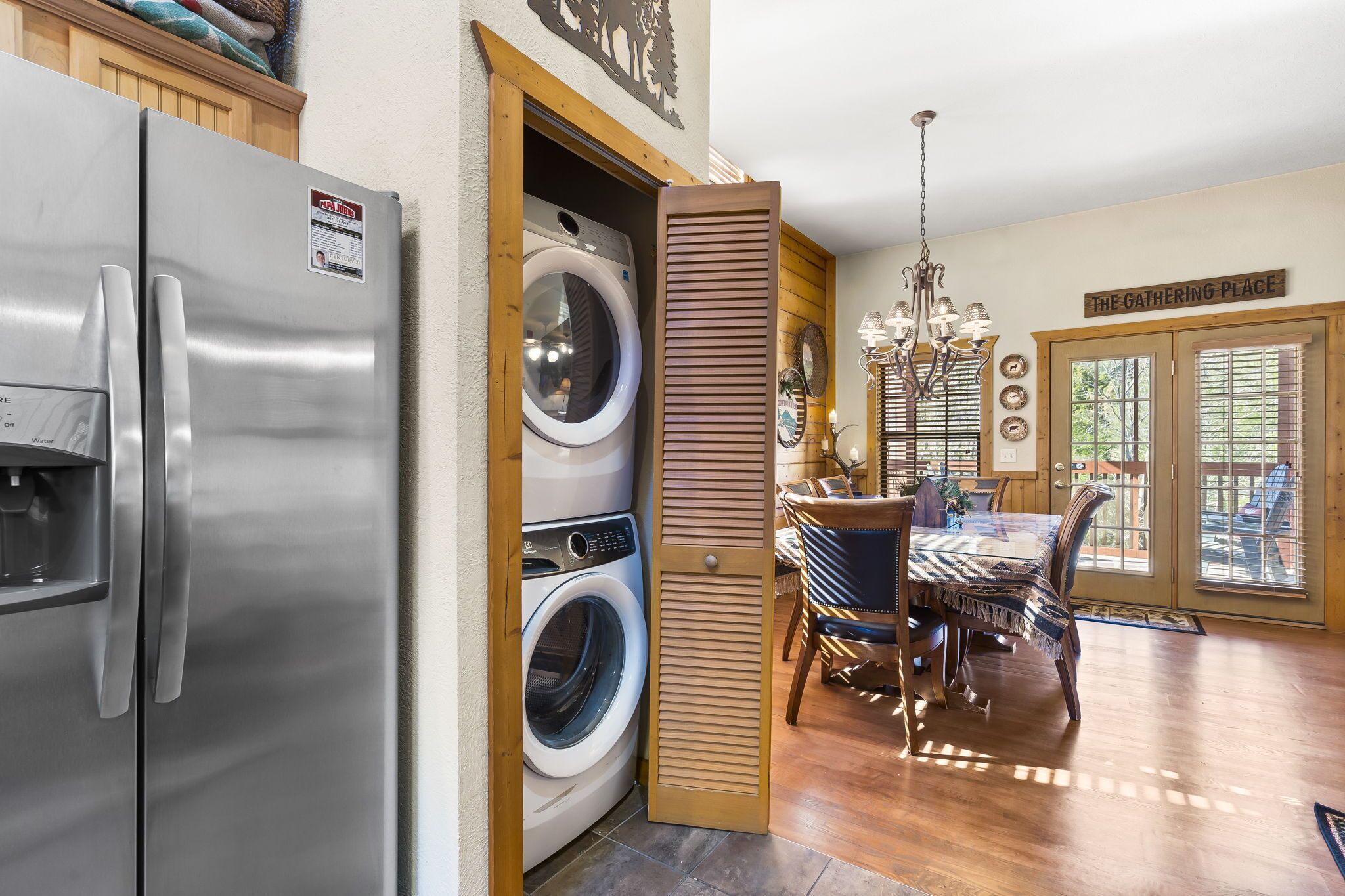 A kitchen with a stainless steel refrigerator, a built-in washer and dryer, and a dining area with a chandelier.