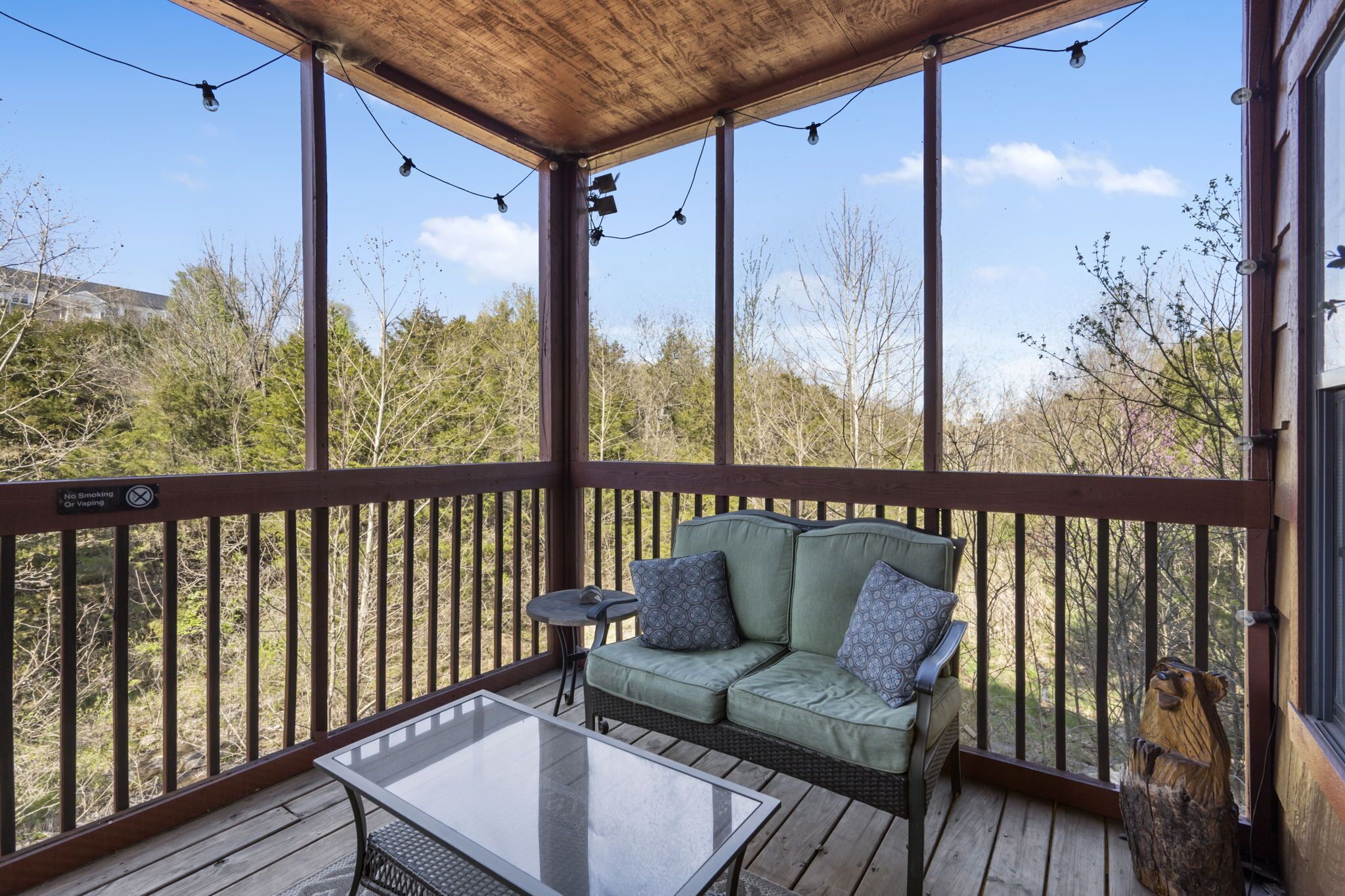 Eine überdachte Terrasse im Freien mit einem grünen Sofa, einem kleinen Tisch und Lichterketten.