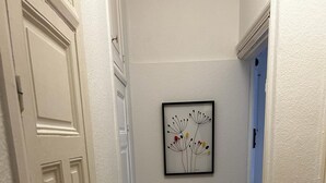 Un couloir doté d’un plancher en bois, de murs blancs et d’une œuvre d’art encadrée accrochée au mur.