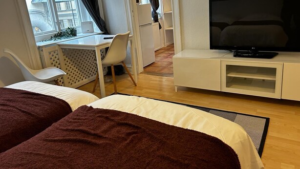 Une chambre d’hôtel avec deux lits, une télévision, un bureau avec une chaise et une vue sur la ville.