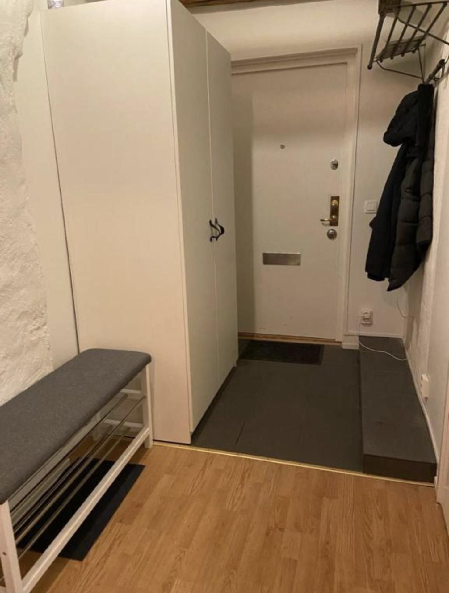 Pequeño cuarto cerrado con un banco, una puerta y un perchero.