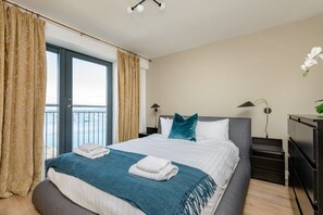 A hotel room with a bed, a view of the sea, and a balcony. - Calming Sea View City Apartment (Edinburgh)