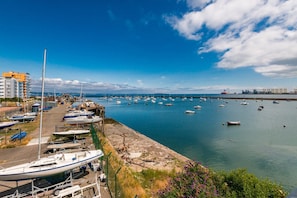 A marina with boats docked, a clear sky, and a distant industrial area. - Calming Sea View City Apartment (Edinburgh)