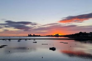A sunset over a calm harbor with boats and a distant city skyline. - Calming Sea View City Apartment (Edinburgh)