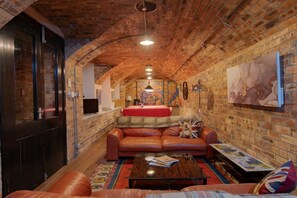 Un coin salon accueillant avec un canapé en cuir, une table basse et un mur d’accent rouge.