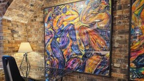 A room with a brick wall, a glass table, a chair, and a painting. - The Armoury: Stylish WW1 Bunker (North Queensferry)