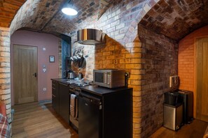 A kitchen with a brick wall, a microwave, a stove, and a refrigerator.